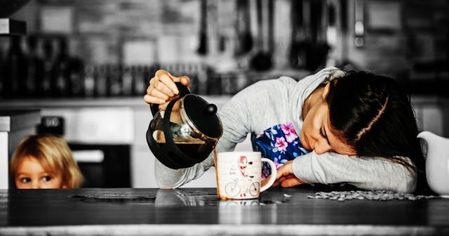 A single mom falling asleep while her child watches her pouring the coffee next to the cup.